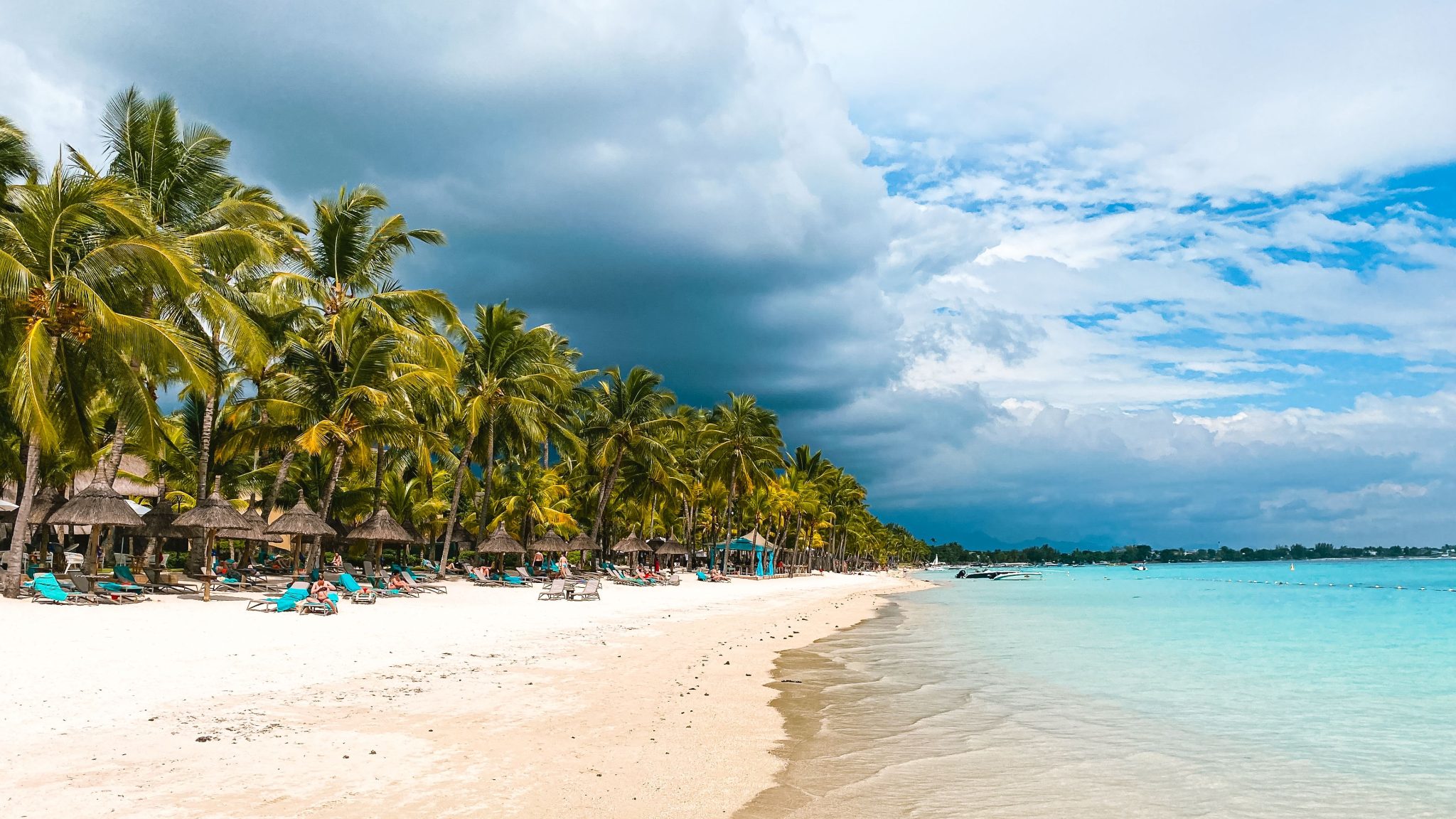 Peaceful tropical beach at Trou-aux-Biches with palm trees and clear waters under a cloudy sky.