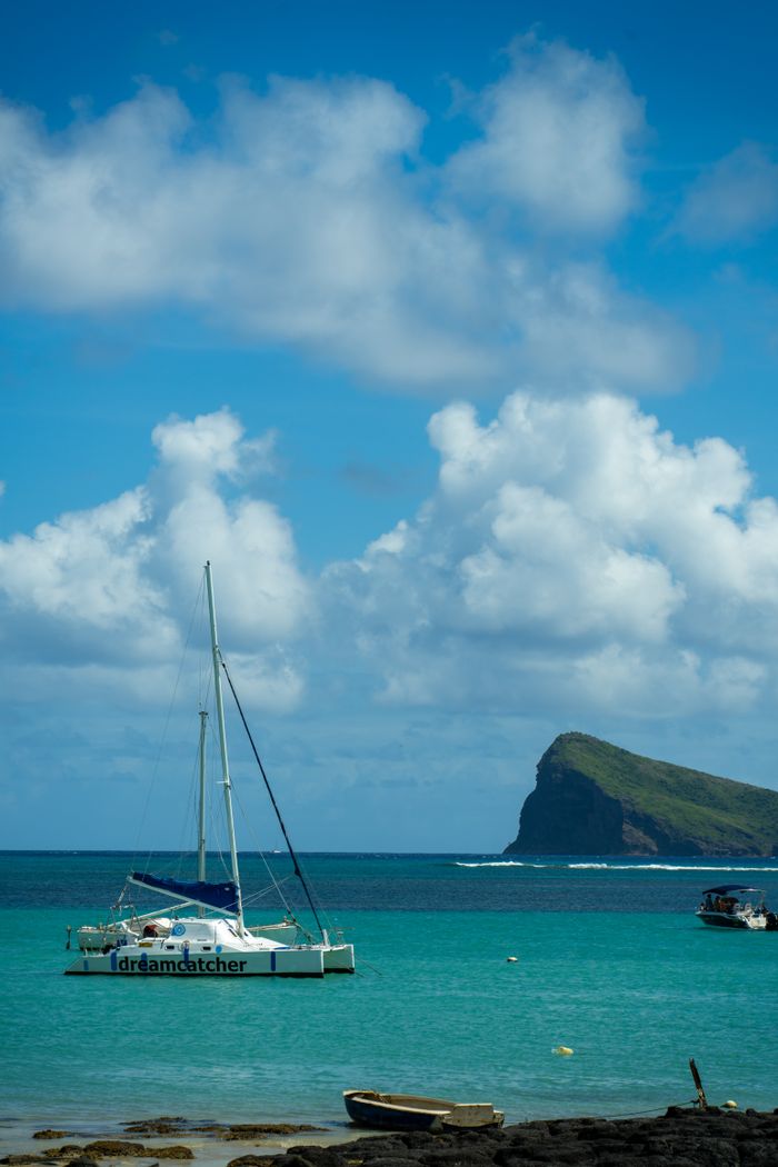 Serene seascape in Mauritius featuring a catamaran and a picturesque island under a vibrant sky.
